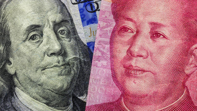Close up of one hundred Dollar and 100 Yaun banknotes with focus on portraits of Benjamin Franklin and Mao Tse-tung/USA vs China trade war concept 