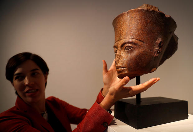 Laetitia Delaloye, head of antiquities of Christie's, poses for a photograph with an Egyptian brown quartzite head of the God Amen prior to its' sale at Christie's auction house in London 