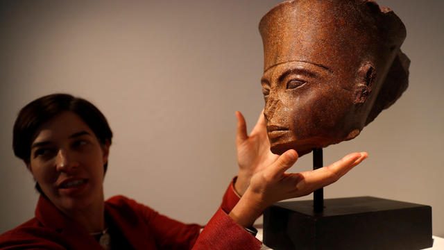 Laetitia Delaloye, head of antiquities of Christie's, poses for a photograph with an Egyptian brown quartzite head of the God Amen prior to its' sale at Christie's auction house in London 