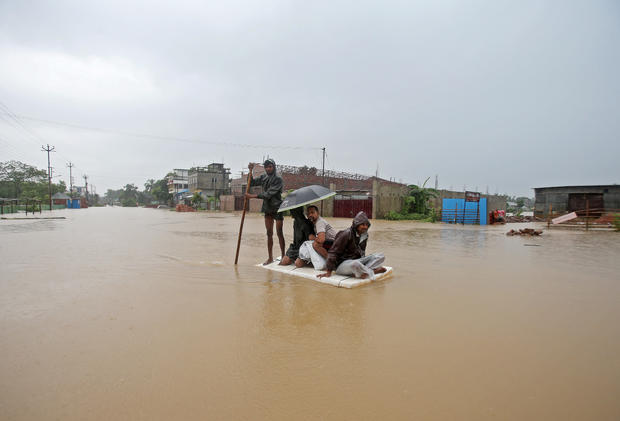 Villagers use a makeshift raft to cross a flooded area on the outskirts of Agartala 