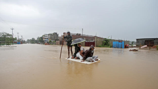 Villagers use a makeshift raft to cross a flooded area on the outskirts of Agartala 