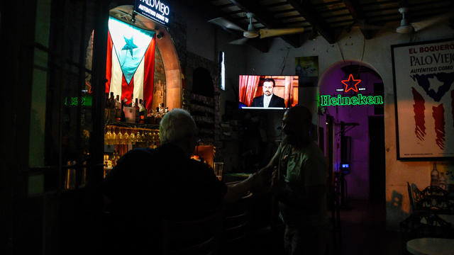 People watch a television broadcast of Puerto Rico's governor Ricardo Rossello's speech at a bar in San Juan 