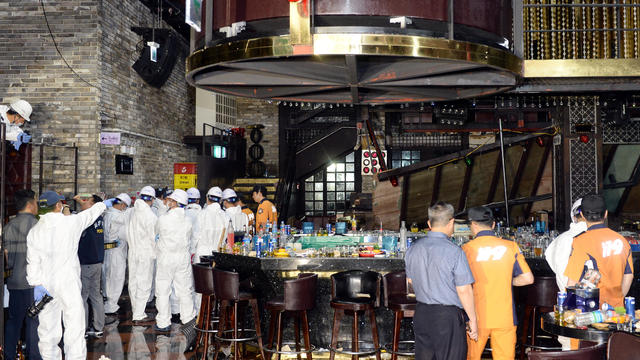 South Korean firefighters and officials examine the collapsed structure of a nightclub in Gwangju 