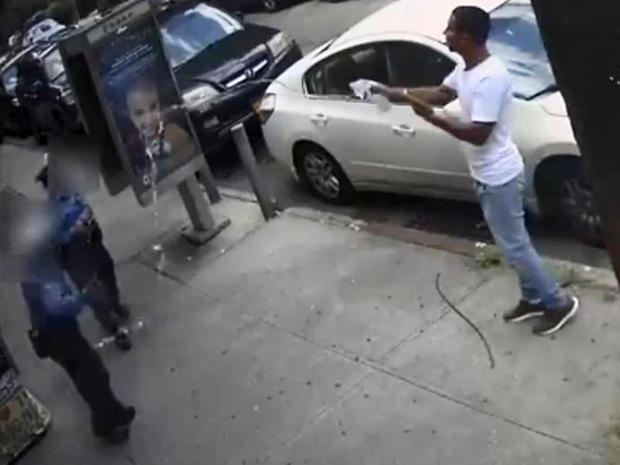 A man throws water at two New York Police Department traffic enforcement agents in the Queens borough of New York City July 24, 2019, in an image capture of surveillance video released by the NYPD Crime Stoppers Program. 