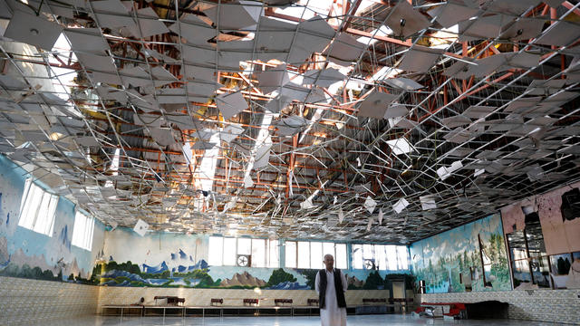 An Afghan man inspects a damaged wedding hall after a blast in Kabul, Afghanistan 