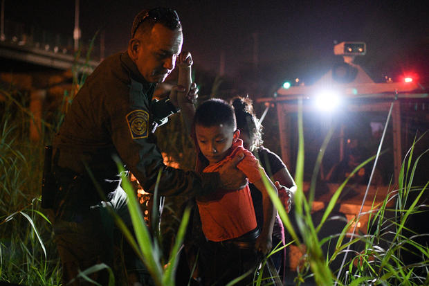 A U.S. Border Patrol agent helps asylum-seeking migrant families unload from a U.S. Border Patrol riverine unit in Hidalgo 