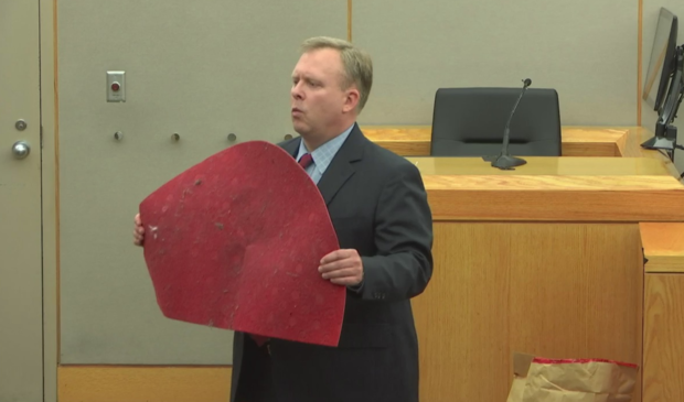 Prosecutor Jason Hermus holds up Botham Jean's red doormat. 