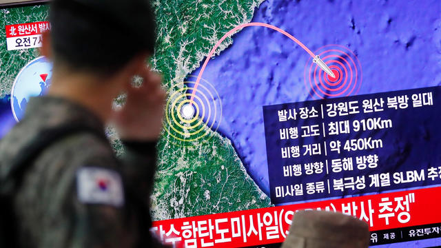 A South Korean soldier walks past a TV broadcasting a news report on North Korea firing a missile that is believed to be launched from a submarine, in Seoul 