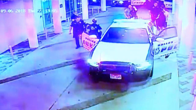 Dallas police Sergeant Mike Mata leads Officer Amber Guyger out of a police car in an image capture from surveillance video September 6, 2018. 