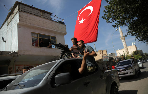 Turkish-backed Syrian rebels drive on a street in the Turkish border town of Akcakale in Sanliurfa province 