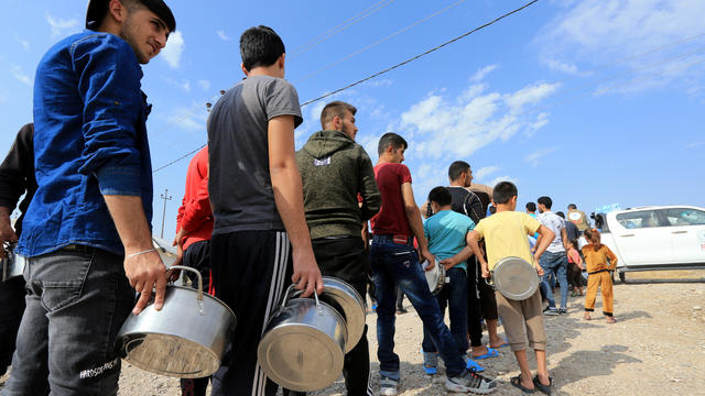 Syrian displaced families, who fled violence after the Turkish offensive in Syria, stand in queue to get their food from Barzani charity at a refugee camp in Bardarash on the outskirts of Dohuk 