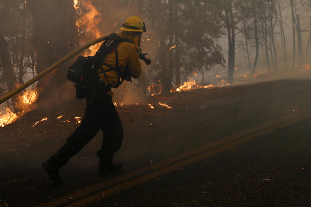 A firefighter pulls a hose along Chalk Hill Road as he battles the wind-driven Kincade Fire in Windsor, California, October 27, 2019. 