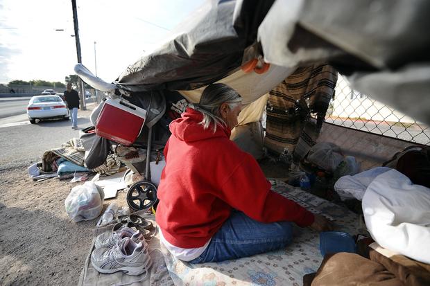A homeless woman plays card in her tent 