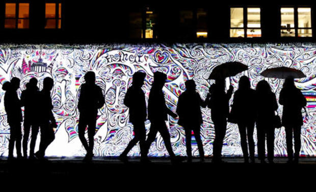 People stand in front of a projection on the East Side Gallery, the largest remaining part of the former Berlin Wall, in Berlin 