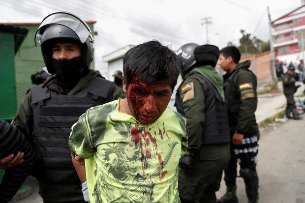 A police officer detains an injured man during clashes between supporters of Bolivian President Evo Morales, who announced his resignation on Sunday, and opposition supporters in La Paz 