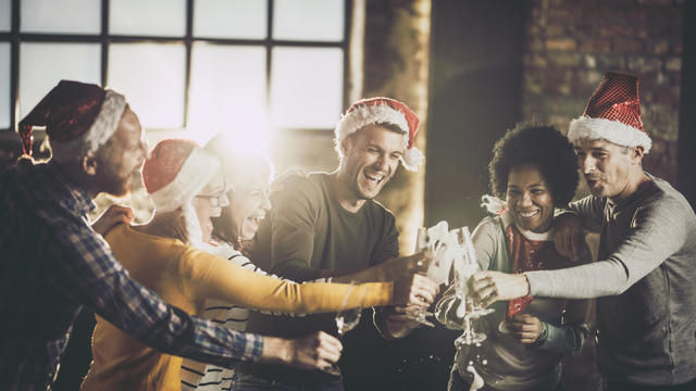 Joyful business team having fun while opening champagne during Christmas celebration in the office. 