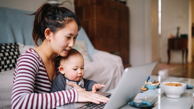 Young Asian mom trying to work with her baby boy 