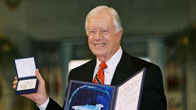 Former President Jimmy Carter holds up his Nobel Peace Prize 