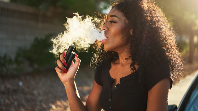 african american woman vaping and exhaling cloud of smoke 