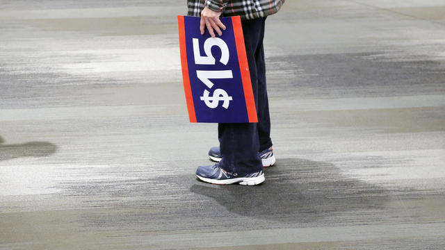 A supporter holds a sign while waiting for the start of a rally to celebrate the state of New York passing into law a $15 minimum wage in New York 