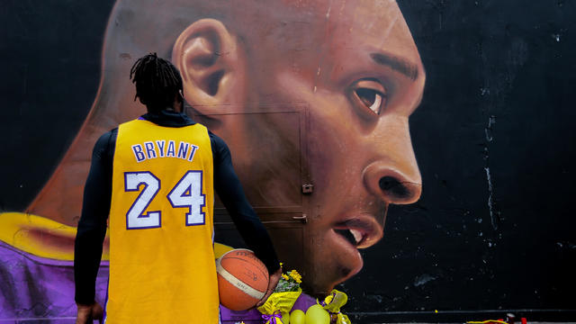 A boy in Kobe Bryant's shirt looks at the mural by Jorit 