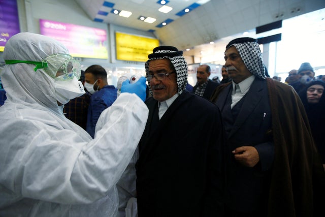 An Iraqi medical staff checks passengers' temperature, amid the new coronavirus outbreak, upon their arrival at Najaf airport