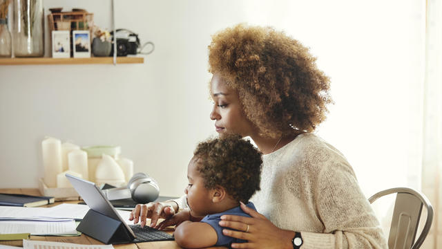 Mother with son working on digital tablet at home 