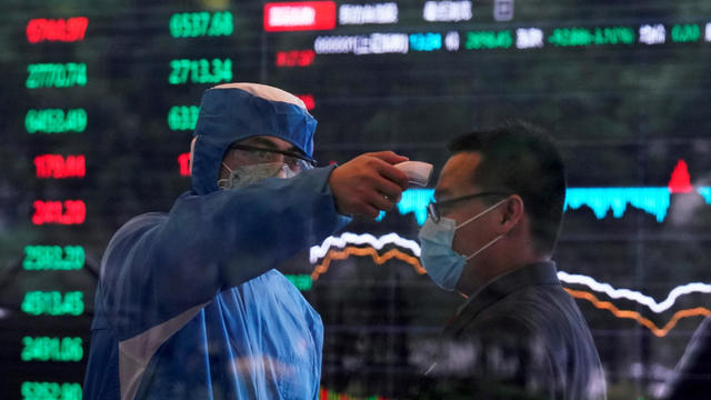 FILE PHOTO: A worker wearing a protective suit takes body temperature measurement of a man inside the Shanghai Stock Exchange building, as the country is hit by a new coronavirus outbreak, at the Pudong financial district in Shanghai 