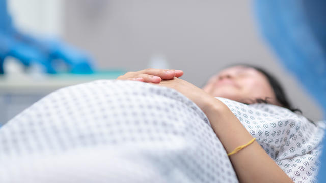 Pregnant woman lays on operating table before receiving cesarean section 