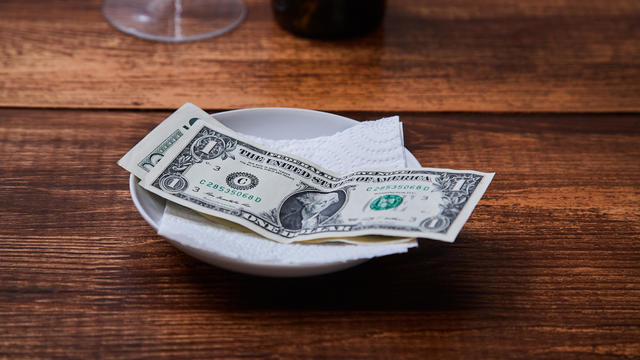 Restaurant tips or gratuity. Banknotes and coins on a plate 