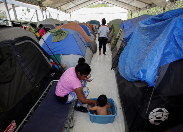 A migrant woman bathes her son outside their tent at a migrant encampment, where more than 2,000 people live while seeking asylum in the U.S, as the spread of the coronavirus disease (COVID-19) continues, in Matamoros 