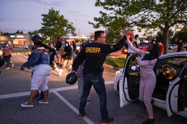 Genesee County Sheriff Chris Swanson high fives a woman who called his name as he marches with protestors of police brutality 