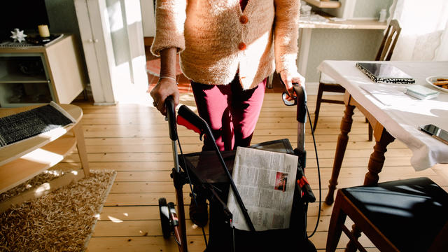 Low section of senior woman walking with rollator at nursing home 