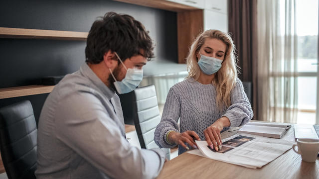 man and woman working with protective masks at home 