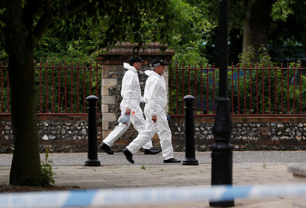 Police officers in forensic suits walk along the park where the scene of multiple stabbings took place, in Reading 