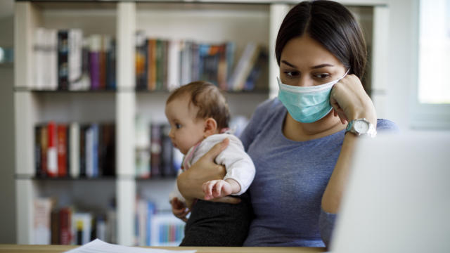 Cropped shot of a young Asian mother using laptop and working from home while taking care of little daughter in self isolation during the Covid-19 health crisis 