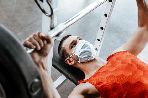 face mask gym exercise selective focus of sportsman in medical mask exercising with barbell in gym 