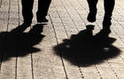 Two women walking down the street, black silhouettes and shadows on pavement 