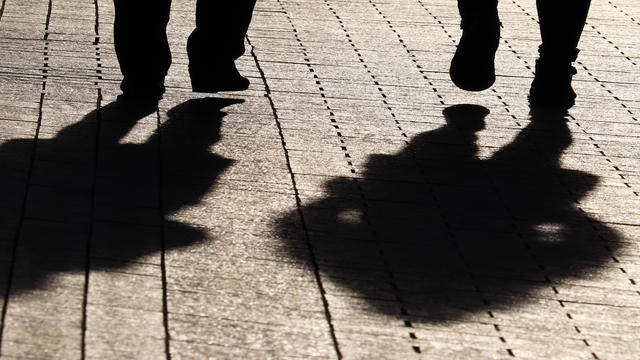 Two women walking down the street, black silhouettes and shadows on pavement 