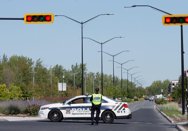 Police officers block a street leading to a condo building in Longueil 