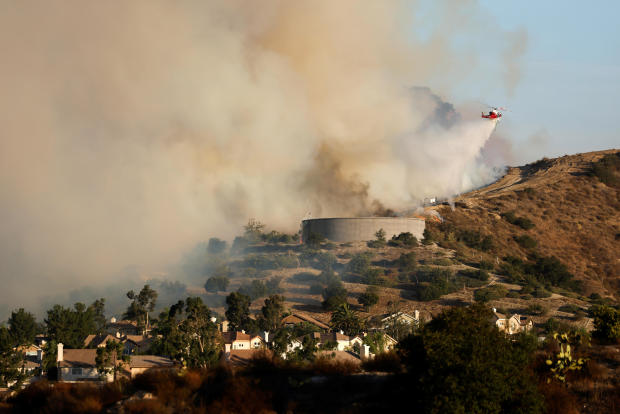 A helicopter drops water over flames from the Silverado Fire near Lake Forest, California, on October 27, 2020. 