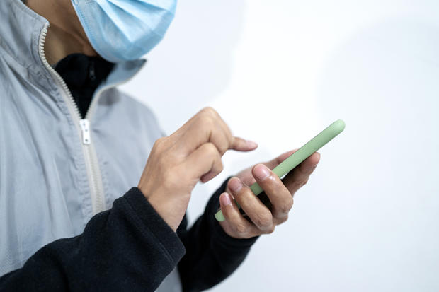 Cold patient wearing protective mask while using mobile phone 