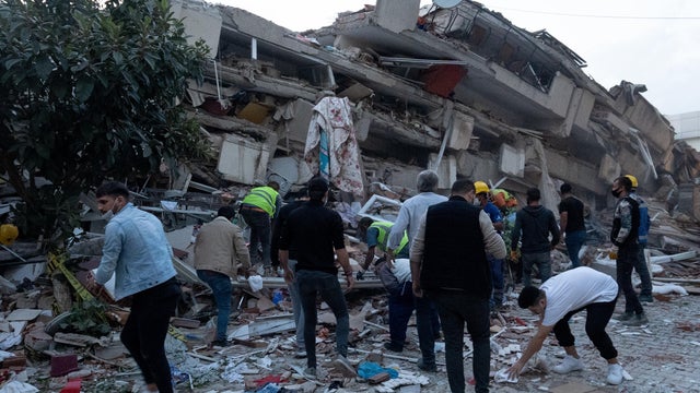 Locals look at a damaged building in Izmir 