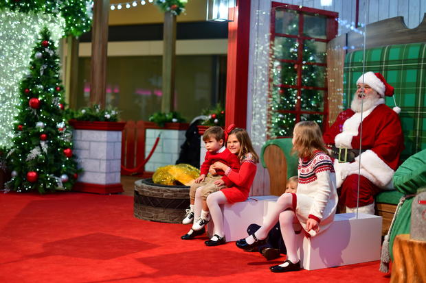 The Matt family (L-R) Jack, 3, Catherine, 8, Sam, 5, and Molly, 9, visit Santa Claus who sits behind a plexiglass divider due to the coronavirus disease (COVID-19) pandemic in Willow Grove 
