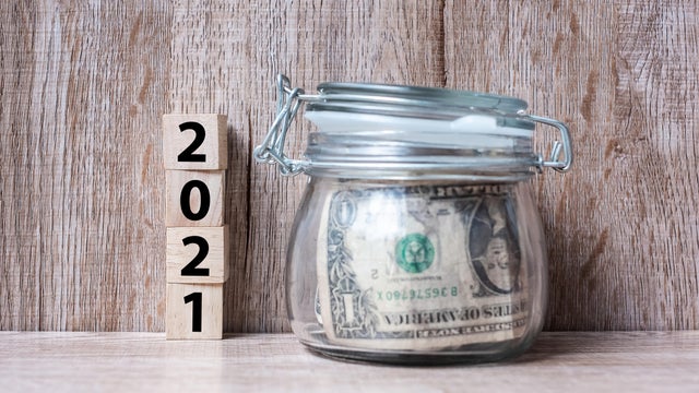2021 Happy New Year with US dollar money glass American on wood table background. business, investment, retirement planning, finance, Saving and New Year Resolution concepts 