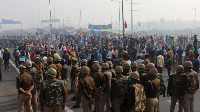 Security officers look on as farmers block the highway 