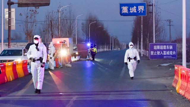 Police officers and staff members inspect vehicles at a checkpoint on the borders of Gaocheng district on a provincial highway 