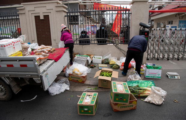 Grocery vendors sell vegetables outside a residential compound entrance in Shijiazhuang, Hebei 