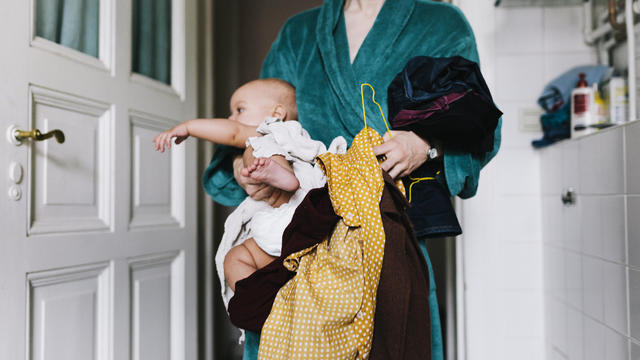Single Mother With Baby Trying To Get Dressed 