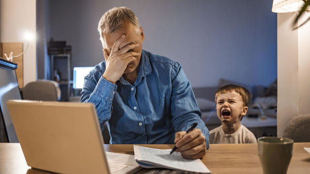 Stressed Man With his two years old son Working From Home 